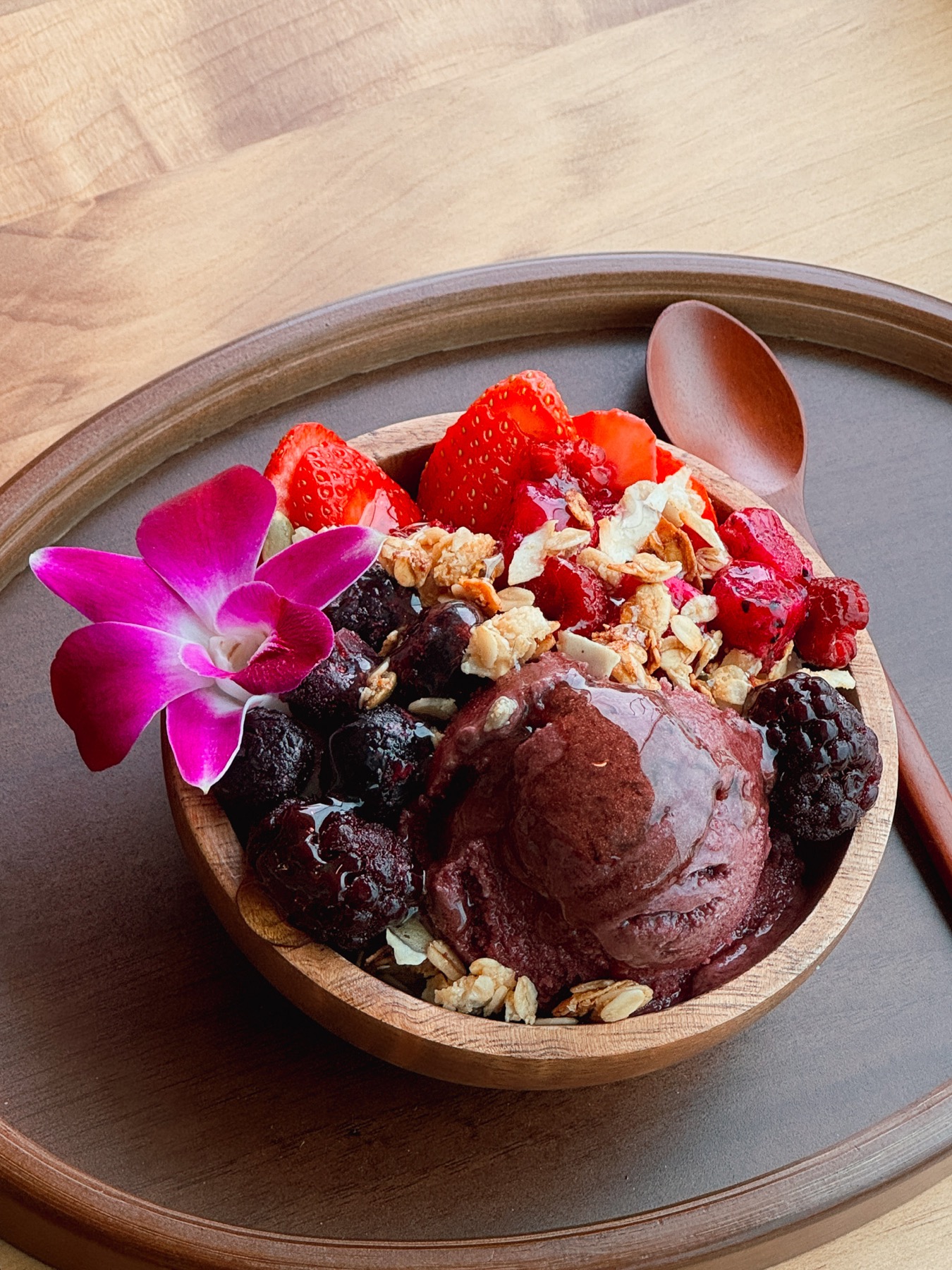 A colorful acai bowl with berries and orchid